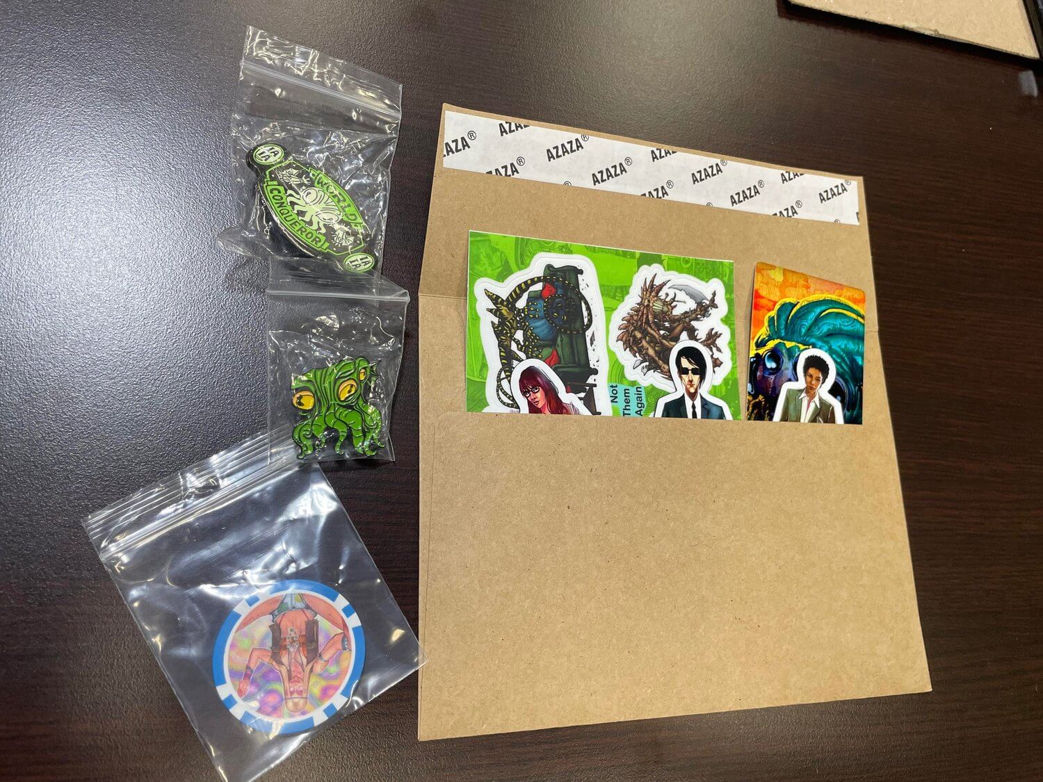 Colorful stickers featuring pop culture characters and creatures, arranged in a craft paper envelope on a brown desk.