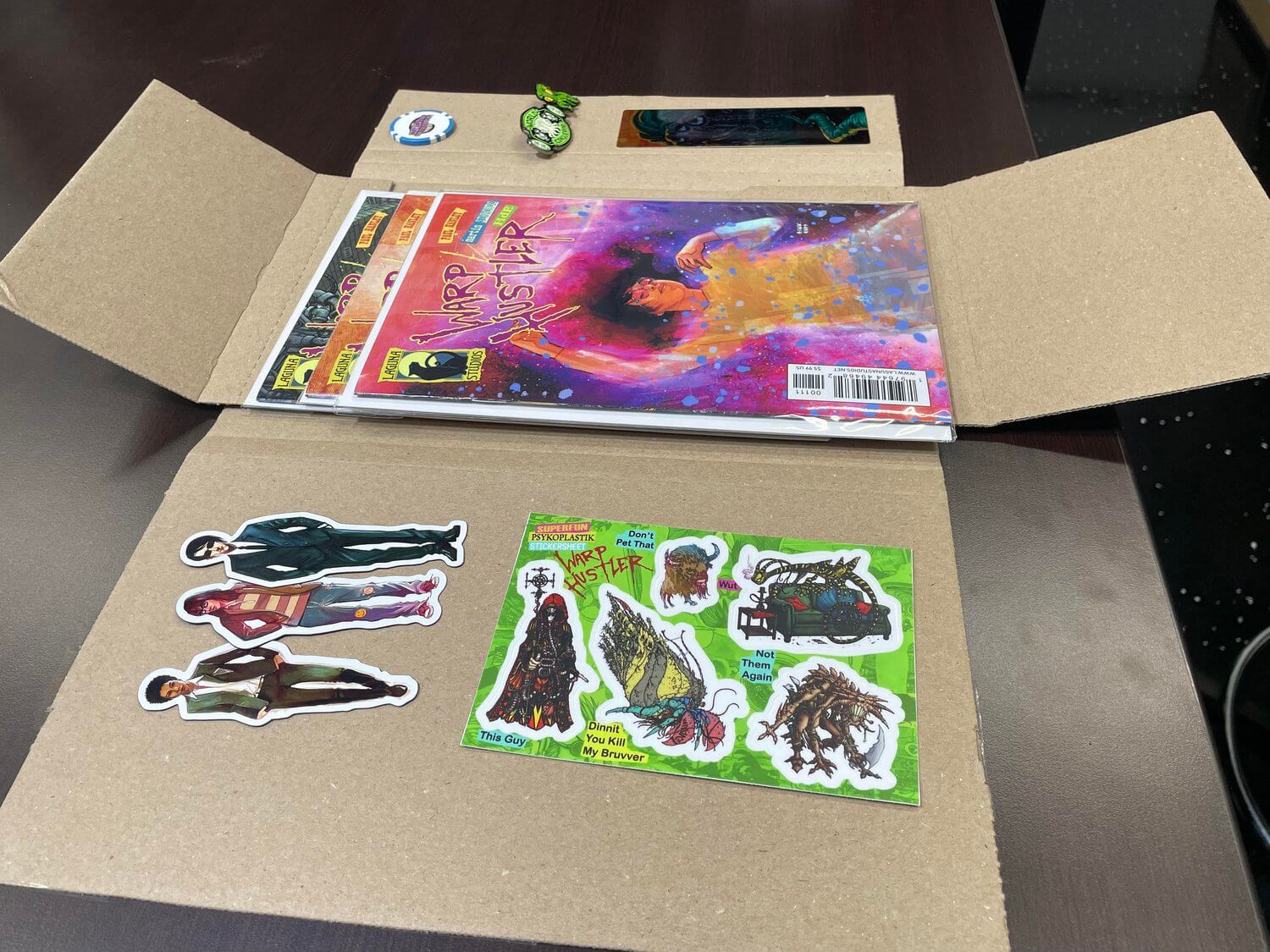Unfolded comic book with colorful stickers on cardboard, showcasing fun designs and characters for collectors.
