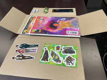 Unfolded comic book with colorful stickers on cardboard, showcasing fun designs and characters for collectors.