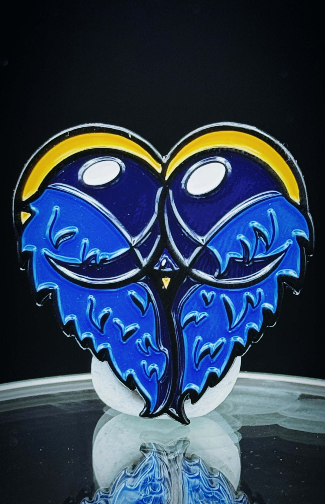 Heart-shaped blue enamel pin with playful design, perfect for comic enthusiasts and team uniforms.