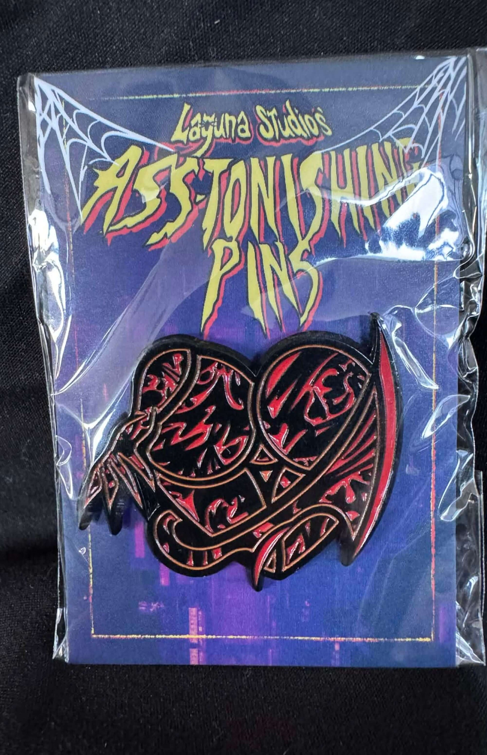 Bloodbath ASS-tonishing Pin displayed in packaging with Laguna Studios branding, showcasing its vibrant design.