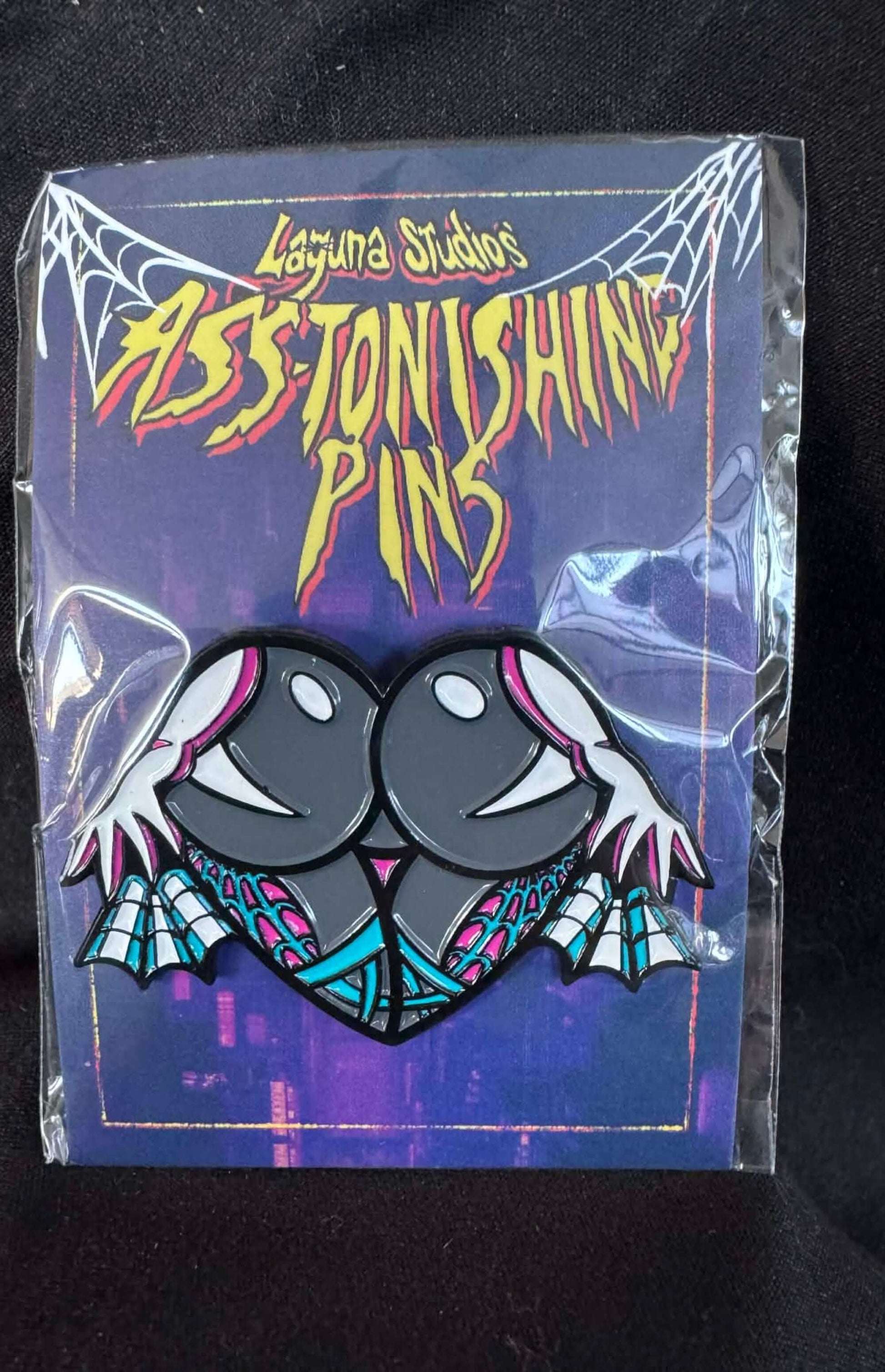 Gwen ASS-tonishing Pin showcased against a colorful comic book style background from Laguna Studios.