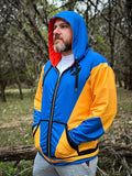 Fainty Telepath Zip-up Hoodie in vibrant blue and yellow worn by a man in a natural setting.