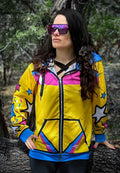 Model wearing Sparkles Zip-up Hoodie, featuring bright colors and 90s comic-inspired design, outdoors with sunglasses.