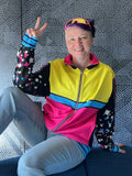 Person wearing the Sparkles Track Jacket, showcasing vibrant colors and playful style, posing with peace sign.